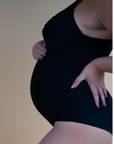 Side view of pregnant mother wearing black one-piece nursing swimsuit 