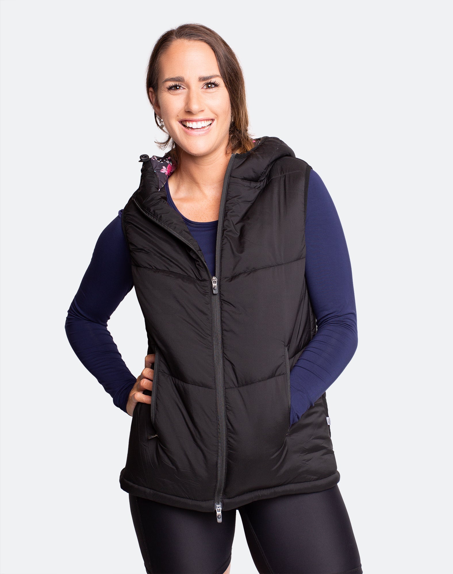 Happy, pregnant mother wearing a women&#39;s black puffer vest