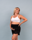 Happy mom holding her baby bump wearing a supportive breastfeeding bra and postpartum shorts