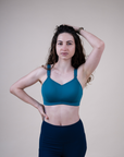 Happy active mother wearing supportive breastfeeding bra in the colour teal