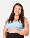 front view of a happy and active pregnant woman showing her bump and nursing sports bra 